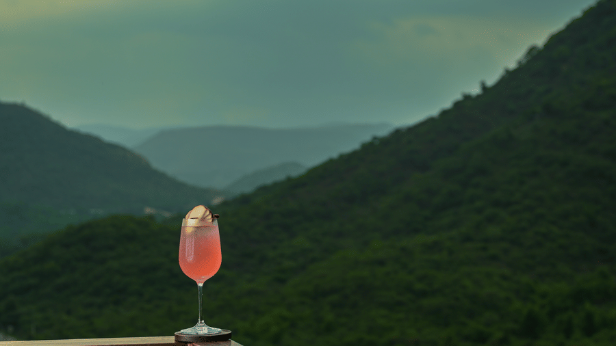 A glass placed on the compound with mountain and sky in the backdrop. | The Ananta Udaipur