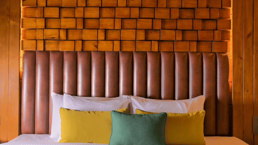 A room at The Ananta Udaipur, featuring a large bed, spreads, pillows, and wooden wall.