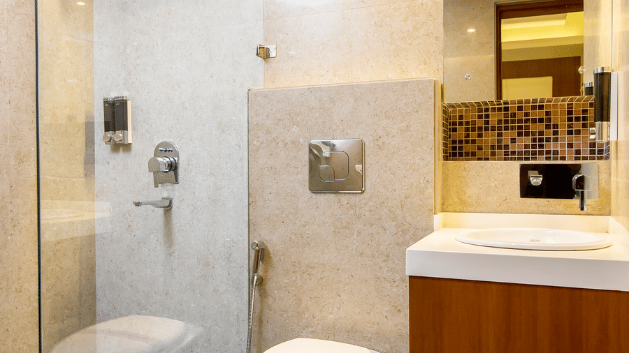 The Onyx bathroom with a glass-enclosed shower area, toilet, washbasin with counter, mirror, and tiled flooring.