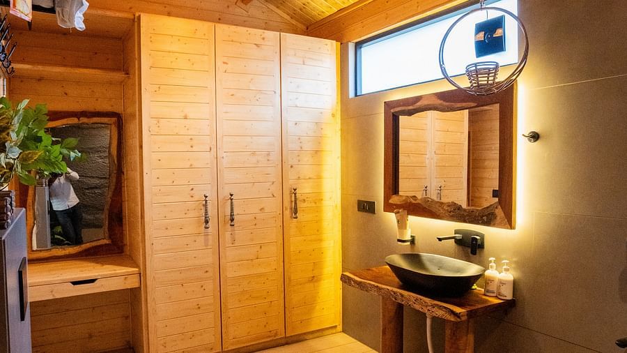 Bathroom at Themis Farm House features a black toilet, a unique dark sink on a wooden stand with a mirror, light wood cabinets, and a wooden ceiling with a fan, creating a stylish and warm ambience.