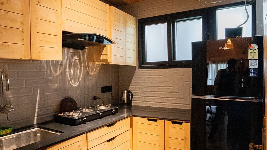 Modern wooden kitchen with sleek black appliances, granite countertops, tiled flooring, and ambient lighting, ideal for a comfortable self-catering stay at Themis Farm House.