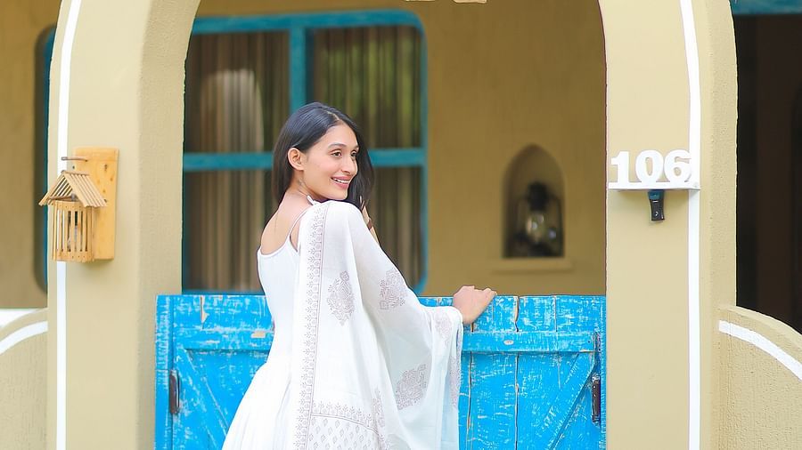 a woman standing by a blue door at Themis Mudhouse - A Nature's Retreat Resort & Wellness