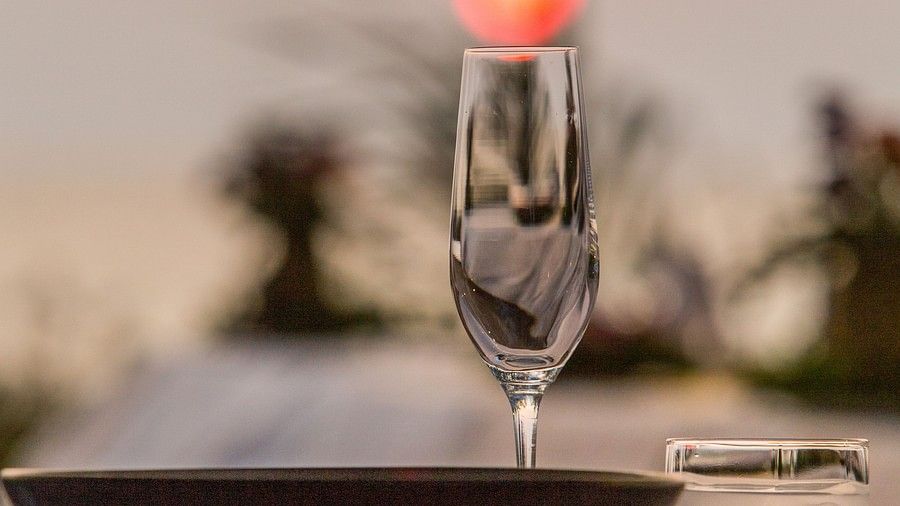 close up image of the champagne glass with a crimson sunset in the background - Maikhao Dream Villa Resort & Spa, Phuket