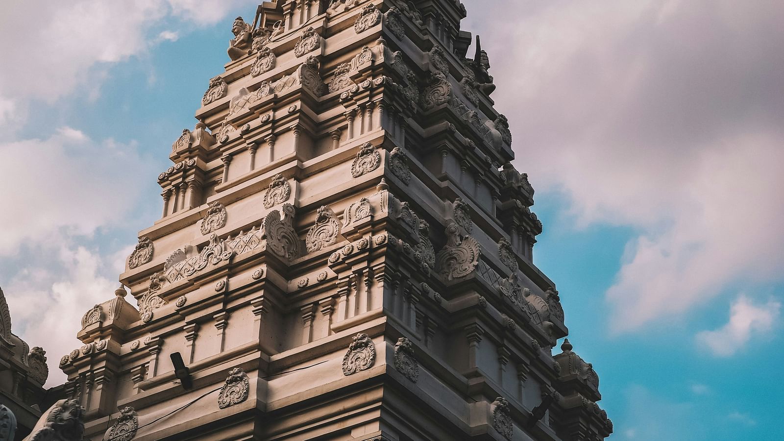 a temple with a huge crown standing tall with a beautiful sky with clouds
