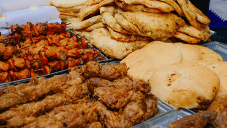 Assorted fried snacks, grilled skewers, and freshly prepared flatbreads displayed at a busy street food stall.