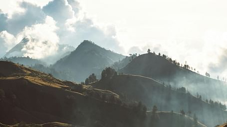Snow-capped mountain peaks rising above misty clouds at sunrise.
