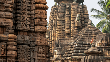 Intricately carved sandstone spires of an ancient Indian temple with a central dome under a pale sky.