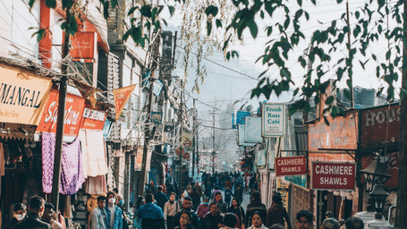 A busy street scene with numerous pedestrians and various buildings lining both sides of the road.