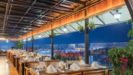 The Hills View restaurant at The Papaya Tree Hotels offering cosy seating with a warm ambience and greenery, perfect for enjoying meals while taking in the outdoor surroundings.