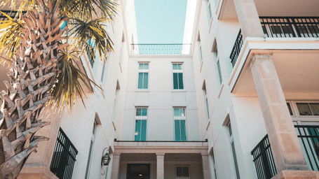 A low-angle shot of a white building with arched doorways under a bright blue sky.