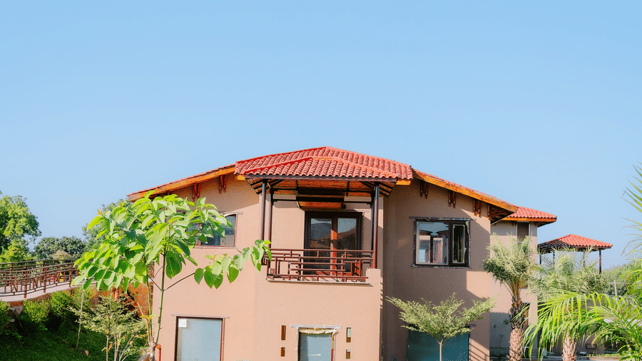 A resort building nestled within a lush green garden under a bright sky at Aamaghati Wildlife Resort.
