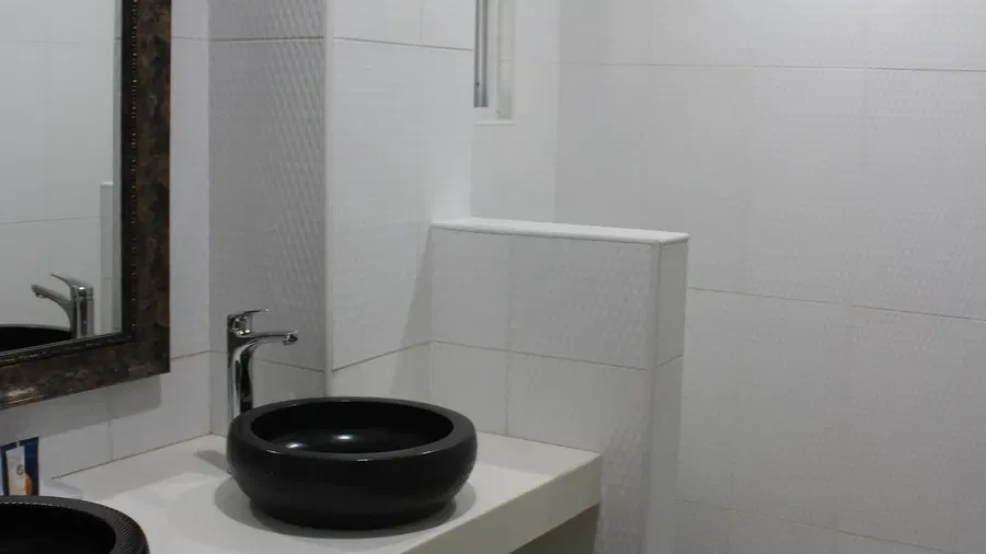 A minimalist bathroom shows a black circular sink on a white vanity with a large mirror above it | Executive King Room | Altamont Court, Jamaica