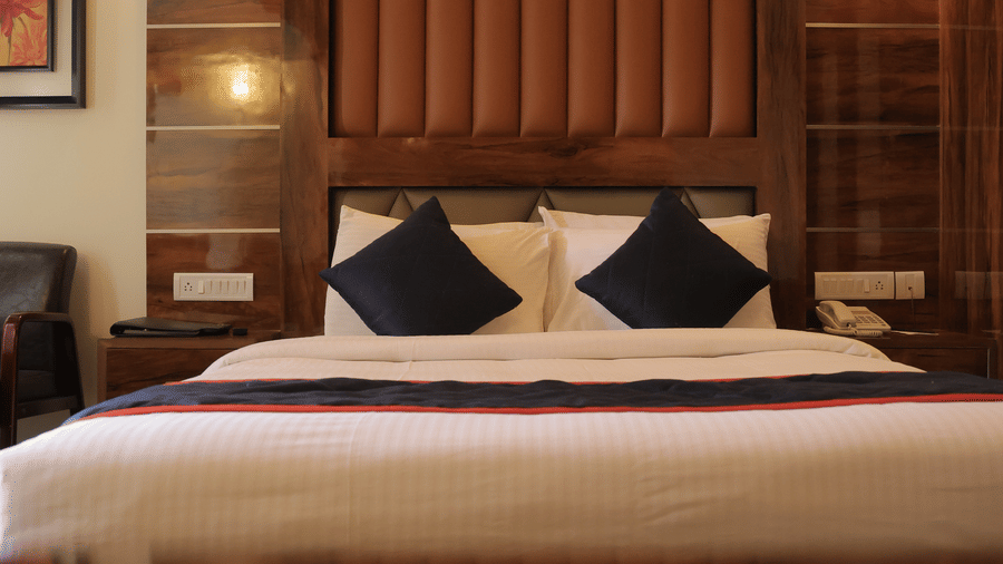 A comfortable hotel bedroom with a neatly made double bed and stylish wooden headboard - Benzz Park, Kodaikanal