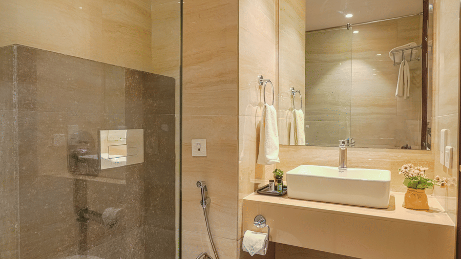 A clean, brightly lit hotel bathroom with a circular sink, large mirror, and a glass-enclosed shower area at BluSalzz Select City Centre, Amritsar.