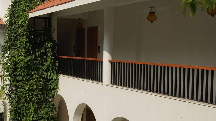 A multi-storey villa featuring arched walkways, railed balconies, climbing ivy at Bougainvillea, Alibaug.