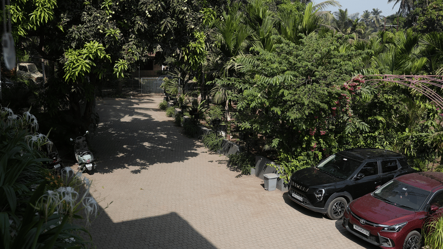 An overhead view of a paved driveway with cars parked next to green trees at Bougainvillea, Alibaug.