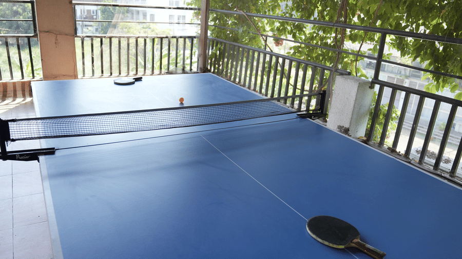 A table tennis table, rackets, and a small ball sit on a tiled terrace at Bougainvillea, Alibaug.