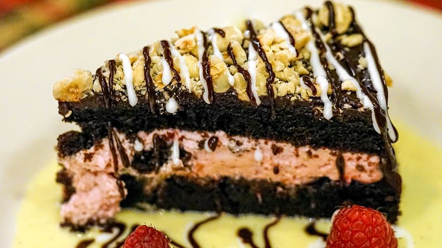 Close-up of a decadent chocolate cake topped with raspberries and a creamy sauce - Brewery Gulch Inn & Spa