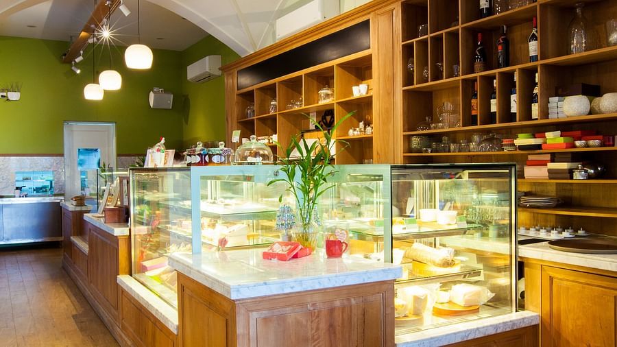 A cafe interior with a counter, display shelves, and a few tables and chairs | The Shop | Central Mansions, Phnom Penh