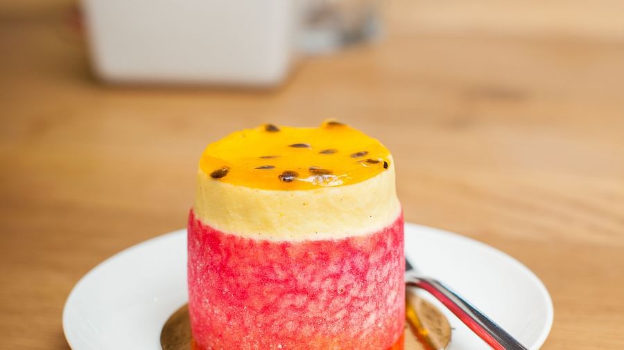 A small cake is on a plate with a spoon nearby placed on a wooden table | The Shop | Central Mansions, Phnom Penh
