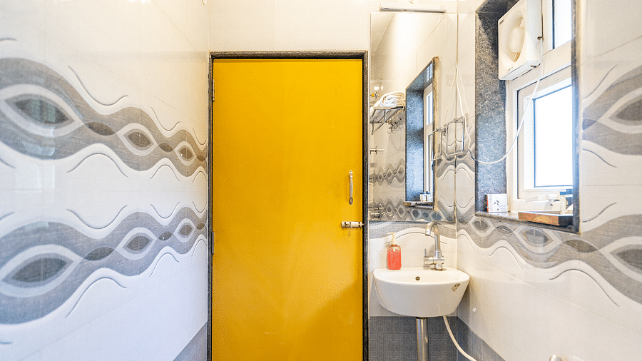 Image of a washroom with a door, a sink and toilet at Coorg Jungle Camp Backwater Resort, Kushalnagar.
