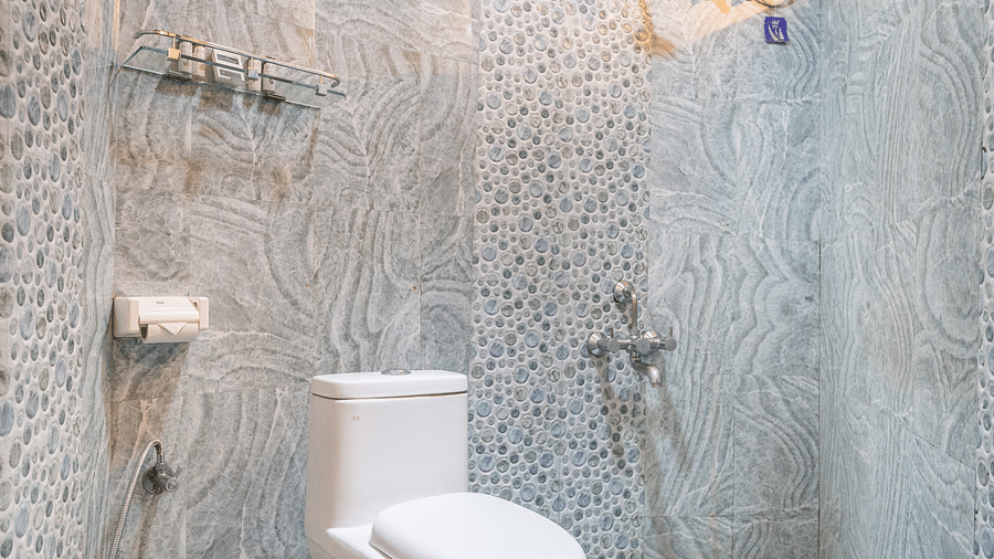 Image of a washroom with a toilet and a geyser mounted on the wall at Coorg Jungle Camp Backwater Resort, Kushalnagar.