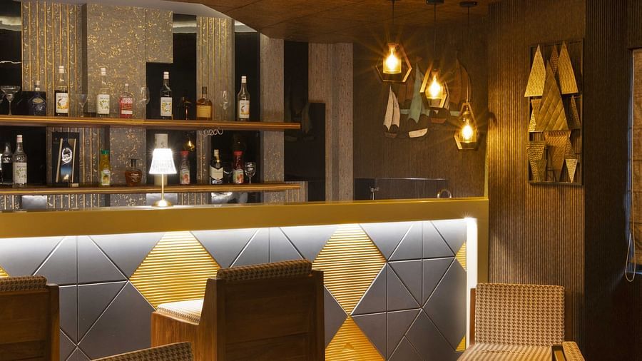 Image of tables and chairs arranged under warm lighting closer to the bar counter at Coral Reef Hotel & Spa in Port Blair