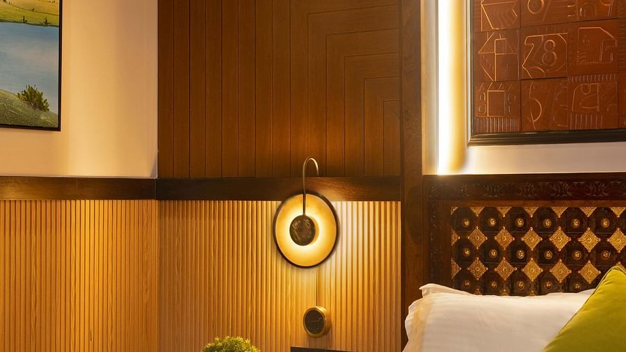 Coral Teal Suite at Coral Reef Resort and Spa in Havelock featuring a plush bed placed against the patterned wall with warm lighting and a nightstand next to it over which is a lamp