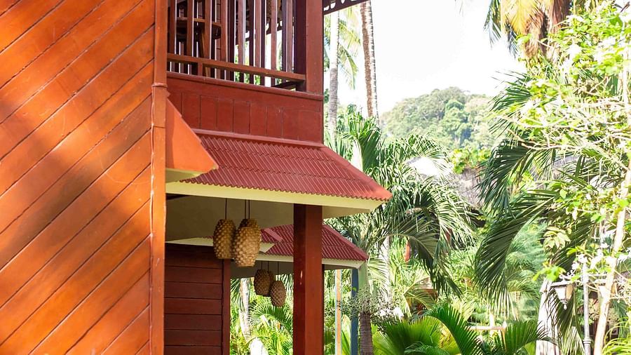 A red building with two levels with greenery around and trees in the background - Coral Reef Resort & Spa, Havelock