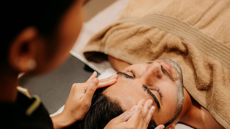 A spa staff member providing a head massage to a man relaxing on the bed at Crescent spa & resort, Indore