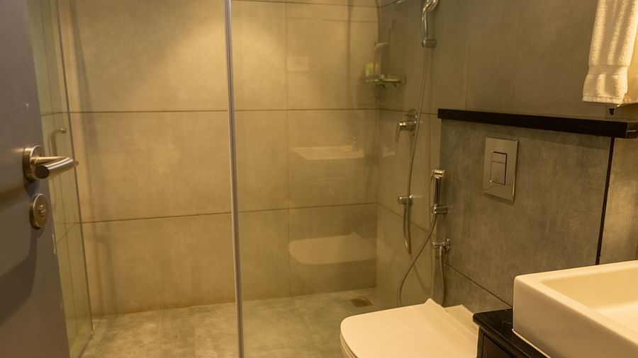 image of the bathroom featuring a shower cubical separated by a glass partition at the luxury group stay villa - Darza Resorts