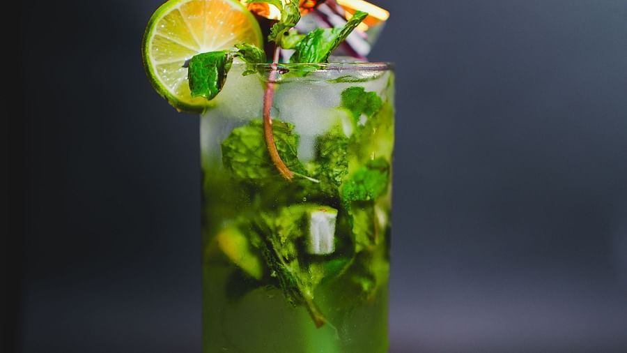 Refreshing green mojito garnished with lime, mint, and a tiny snack pack — a vibrant beverage creation from D Café at Dip Holidays.