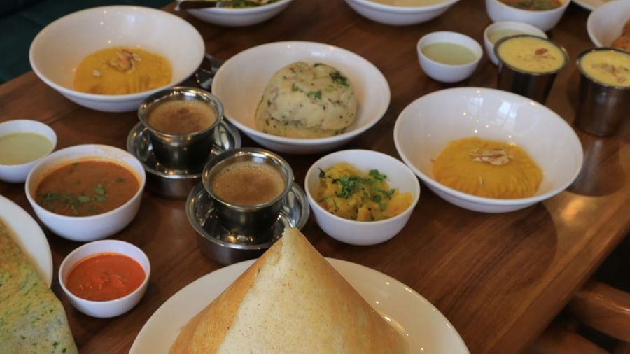 South Indian breakfast spread with dosa, idli, vada, multiple chutneys, and sambar served on a wooden table at Fireflies Resorts, Kabini.