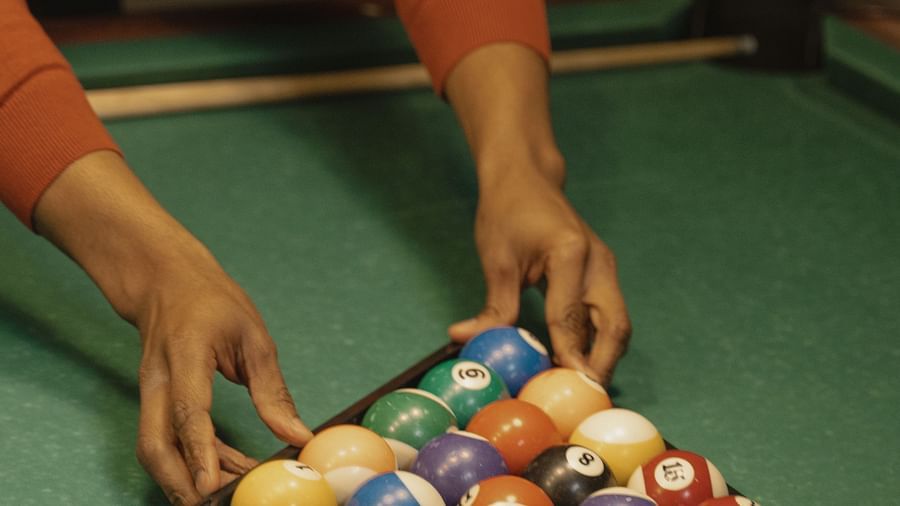 A hand arranging pool balls at a Pool Table