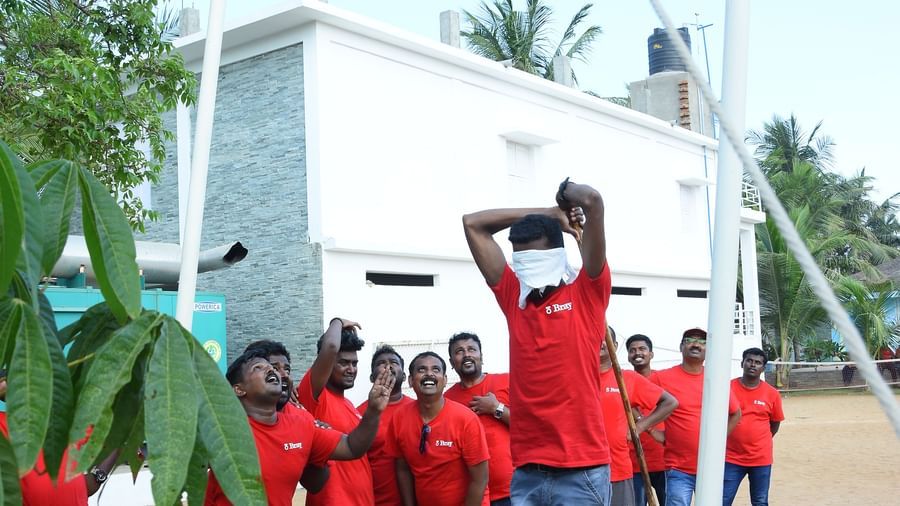 A person trying to break a clay pot with other people at the background in an outdoor area at Grande Bay Resort & Spa.
