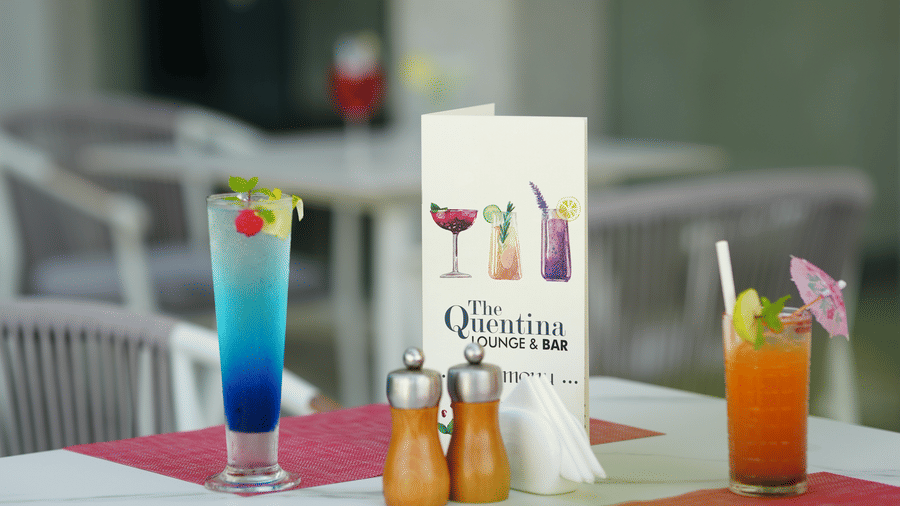 Outdoor cafe table setup from The Quentina Bar featuring cocktails and a menu card - Grande Bay Resort & Spa, Mamallapuram