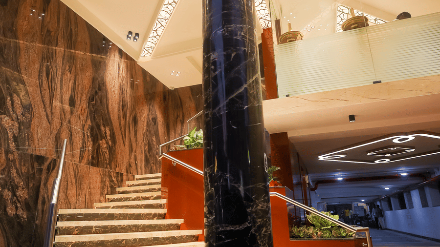 Marble spiral staircase with a central support pillar and ceiling lights inside the lobby at Hotel Grand Sabarees Madurai.