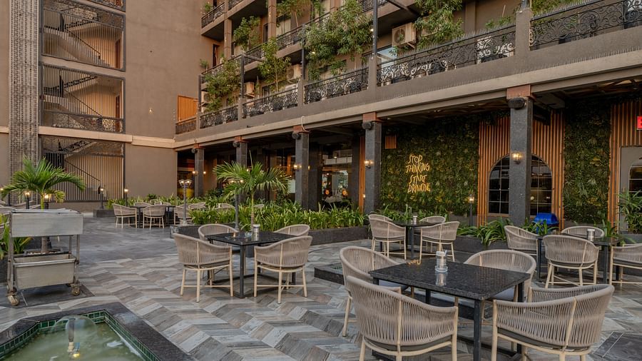 Courtyard seating area at Hotel Highway King, Bagru, with tables, chairs, fountains, and surrounding hotel balconies.