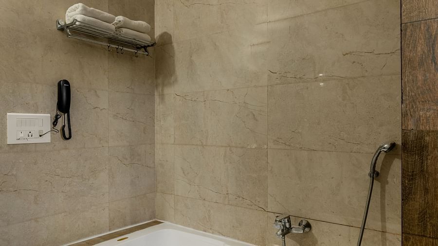Bathtub with a hand shower, towel hanger and other necessary fittings in the bathroom of the Suite in Hotel Highway King in Behror.