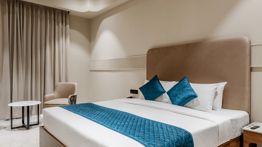 A king size bed, an armchair with a table, and a ceiling fan at Hotel Highway King, Harmada.