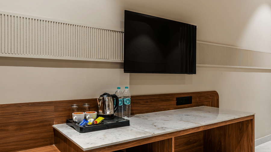 A wooden desk with a mini fridge, a television, and a waste bin at Hotel Highway King, Harmada.