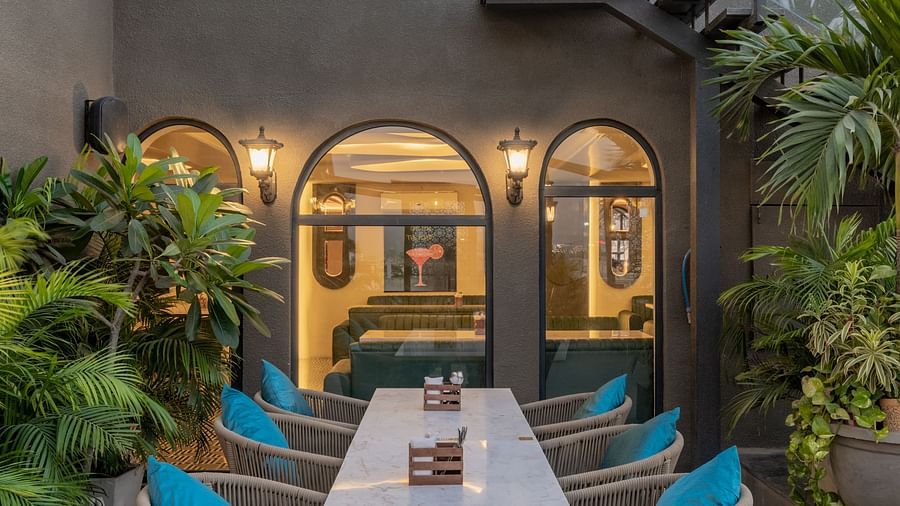 Rooftop dining corner with wall lantern, arched windows, and planters at Hotel Highway King, Jaipur.
