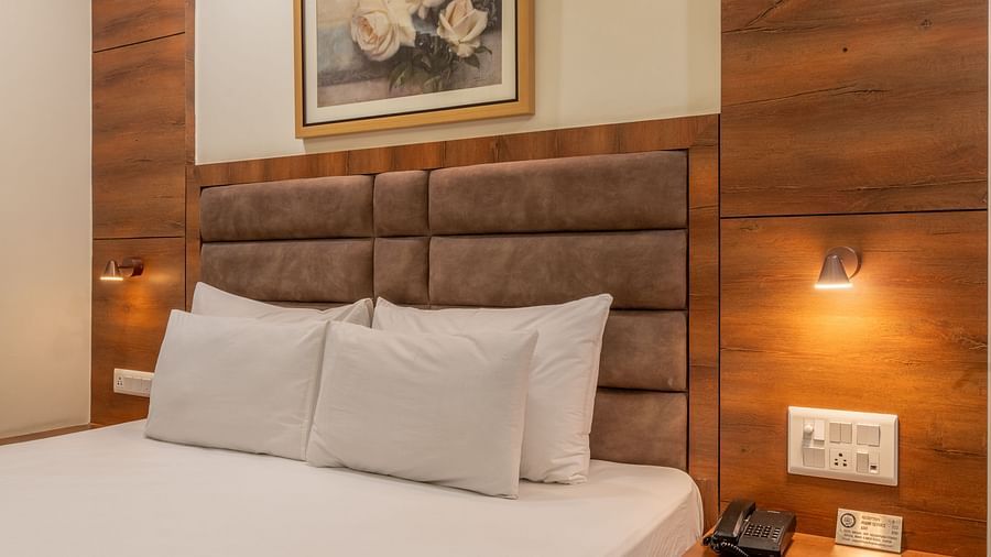 A corner view of a room, featuring a king size, wall art, and a bedside table at Hotel Highway King, Jaipur.