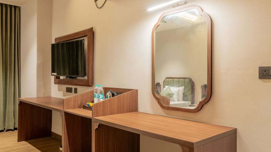 Stylish room with a dressing table, mirror, and wooden furnishings under soft lighting at Hotel Highway King, Neemrana.