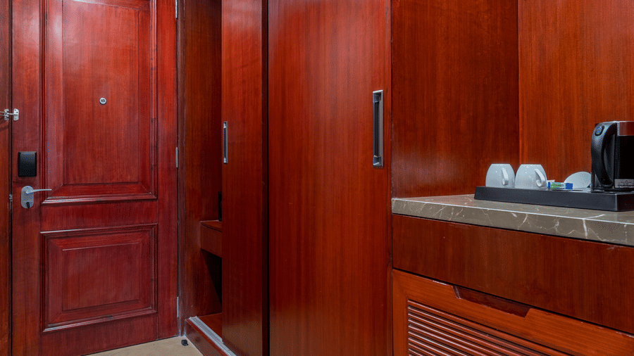 Small interior space or hallway with rich, dark mahogany wood panelling and cabinetry, leading to another room at Hotel Hukam's Lalit Mahal.