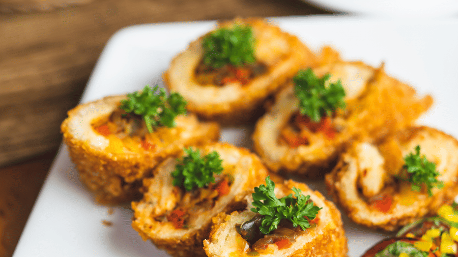 Close-up of an appetiser dish—fried rolls or snacks—served with a tangy dipping sauce on a white platter at Hotel Hukam's Lalit Mahal.