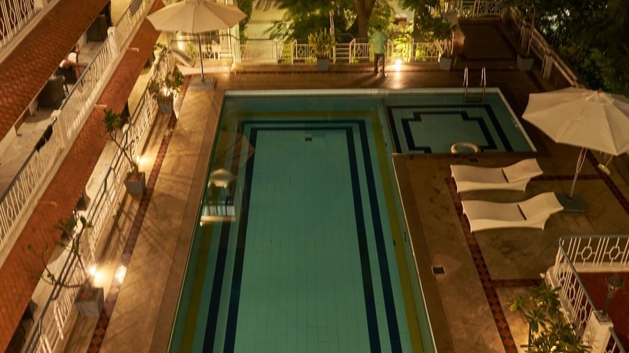 A serene nighttime view of the swimming pool at Hotel Mamallaa Heritage, with white umbrellas illuminated by soft lights around the pool.