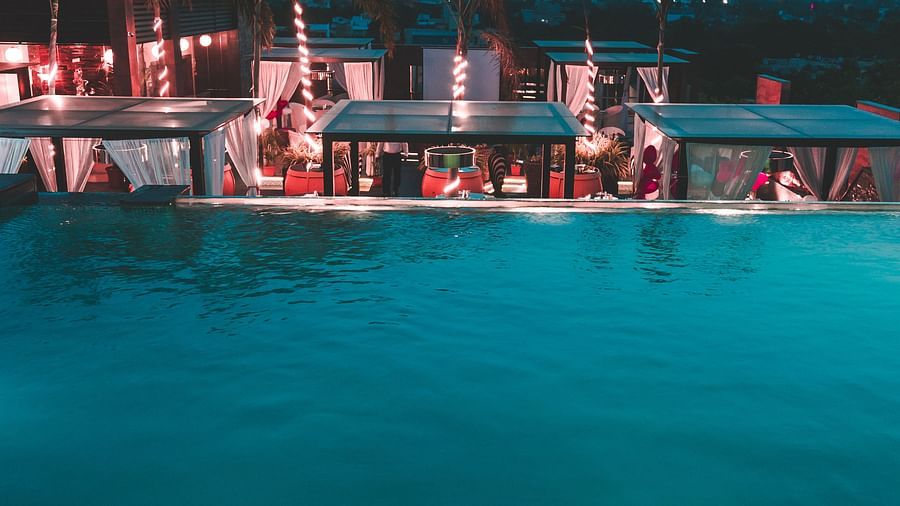 a view of a restaurant with an infinity pool beside and tents kept on the poolside - Hotel Park Elanza, Chennai