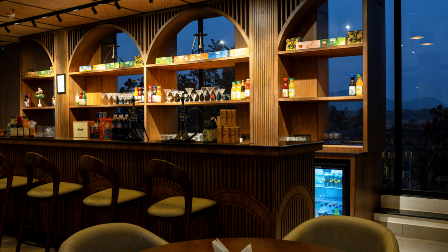 An indoor area featuring a round table, chairs, and a curved wooden bar counter at Hotel Sonar Bangla, Ajodhya Hills.