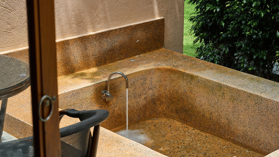 A view through a doorway featuring an outdoor stone bathtub and a chair at Hotel Sonar Bangla, Ajodhya Hills.